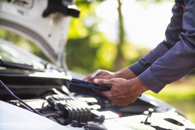 Araç hizmet merkezi tamircileri araba ve motoru kontrol ediyor. Kullanıma hazır ve merkezin garantisine göre mükemmel durumda olduklarından emin olun. Güvenli sürüş için periyodik araç denetimleri.