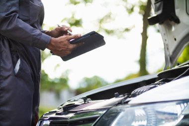 Araç hizmet merkezi tamircileri araba ve motoru kontrol ediyor. Kullanıma hazır ve merkezin garantisine göre mükemmel durumda olduklarından emin olun. Güvenli sürüş için periyodik araç denetimleri.