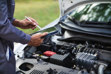 Araç hizmet merkezi tamircileri araba ve motoru kontrol ediyor. Kullanıma hazır ve merkezin garantisine göre mükemmel durumda olduklarından emin olun. Güvenli sürüş için periyodik araç denetimleri.
