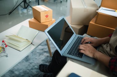 İş adamı, dizüstü bilgisayar ve akıllı telefon kullanarak evde küçük KOBİ işletmelerine yatırım yapmaya karar veriyor ve siparişlere göre ürün paketlemeden önce bir uygulama aracılığıyla online pazarlama yapıyor ve bir şeyler satıyor..