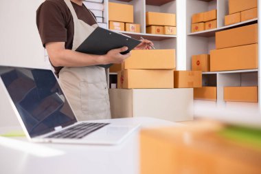 İş adamı, dizüstü bilgisayar ve akıllı telefon kullanarak evde küçük KOBİ işletmelerine yatırım yapmaya karar veriyor ve siparişlere göre ürün paketlemeden önce bir uygulama aracılığıyla online pazarlama yapıyor ve bir şeyler satıyor..