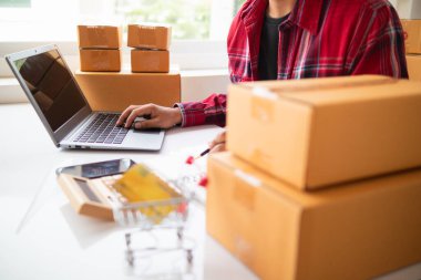 İş adamı, dizüstü bilgisayar ve akıllı telefon kullanarak evde küçük KOBİ işletmelerine yatırım yapmaya karar veriyor ve siparişlere göre ürün paketlemeden önce bir uygulama aracılığıyla online pazarlama yapıyor ve bir şeyler satıyor..