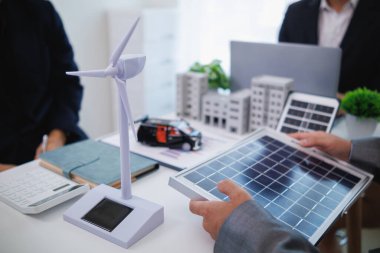 Mimarlar ve yatırımcılar konut inşaatı projelerinde temiz enerji veya güneş pilleri kullanarak emlak projelerini tartışıyorlar. Büyük konut inşaat projelerinde temiz enerji kullanımı kavramı.