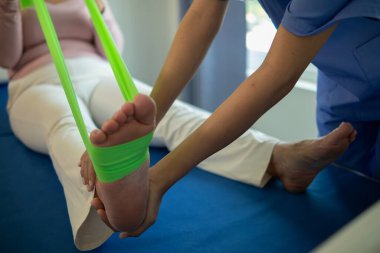 Lastik bant kullanan kadın doktor kas hasarını atlattıktan sonra kas hareketlerinin düzelmesine yardım ediyor ve günlük yaşamını fizik tedavi uygulayarak kullanabilmesini istiyor.