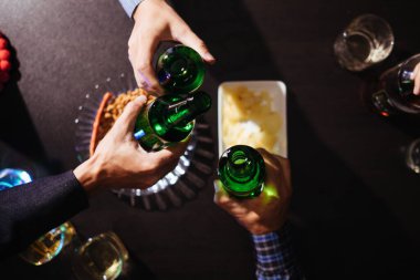 Bir grup işadamı, ortak iş girişimlerinin başarısını kutlamak için ellerinde bira şişeleri ve tokuşturarak birlikte bira içerek başarıyı kutluyorlar..