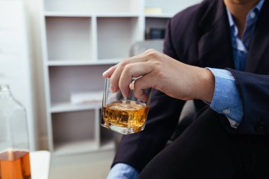 İş adamı, tatmin edici bir sonuca ulaşana kadar yatırımcılarla görüşüp iş yapmayı kabul ettikten sonra ofisinde tek başına oturmuş brendi içiyor. Brendiyle rahatlama konsepti