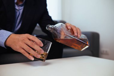 İş adamı, tatmin edici bir sonuca ulaşana kadar yatırımcılarla görüşüp iş yapmayı kabul ettikten sonra ofisinde tek başına oturmuş brendi içiyor. Brendiyle rahatlama konsepti