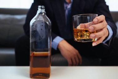 İş adamı, iş hayatında sorunlar yaşadıktan sonra stres atmak için elinde içki bardağıyla oturur. Alkol alan işadamı, başarısız iş girişiminin stresinden kurtuldu.