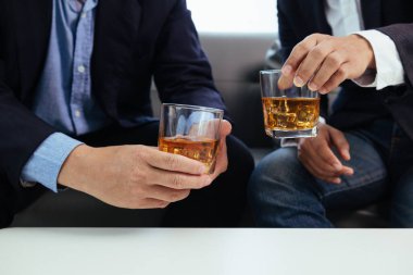 Bir grup işadamı brendi bardaklarını bir arada tutarak, ticari girişimler ve ortak iş karları konusunda tatmin edici bir anlaşmaya vardıktan sonra brendi kadehlerini bir araya getirdi..