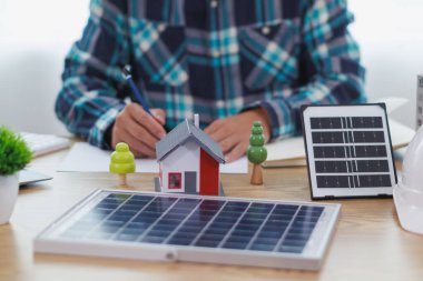 Mühendisler, güneş panelleri ve rüzgar türbinlerini güneş pillerinden gelen yeşil enerji kavramını kullanarak verimli bir şekilde elektrik üretmek üzere binaya yerleştirmeye hazırlanmak için mimarların planlarını gözden geçiriyorlar.