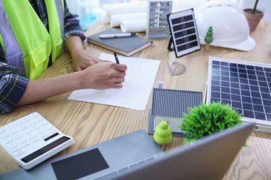 Mühendisler, güneş panelleri ve rüzgar türbinlerini güneş pillerinden gelen yeşil enerji kavramını kullanarak verimli bir şekilde elektrik üretmek üzere binaya yerleştirmeye hazırlanmak için mimarların planlarını gözden geçiriyorlar.