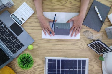 Mühendisler, güneş panelleri ve rüzgar türbinlerini güneş pillerinden gelen yeşil enerji kavramını kullanarak verimli bir şekilde elektrik üretmek üzere binaya yerleştirmeye hazırlanmak için mimarların planlarını gözden geçiriyorlar.