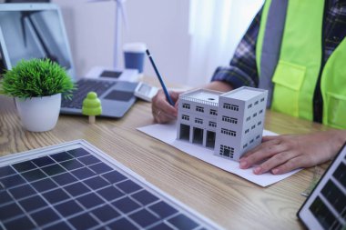 Mühendisler, güneş panelleri ve rüzgar türbinlerini güneş pillerinden gelen yeşil enerji kavramını kullanarak verimli bir şekilde elektrik üretmek üzere binaya yerleştirmeye hazırlanmak için mimarların planlarını gözden geçiriyorlar.