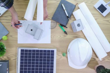 Mühendisler, güneş panelleri ve rüzgar türbinlerini güneş pillerinden gelen yeşil enerji kavramını kullanarak verimli bir şekilde elektrik üretmek üzere binaya yerleştirmeye hazırlanmak için mimarların planlarını gözden geçiriyorlar.