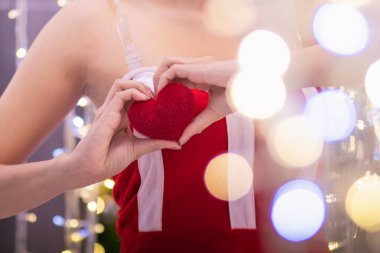 Kadın, bulanık arka planda aşkı ve arkadaşlığı temsil eden bir kalp sembolü yapmak için ellerini kaldırır. Elleri kullanarak kalp sembolü yapmak dostluğun, sevginin ve iyiliğin anlamını temsil eder..