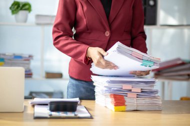 Sekreterin şirket yönetim kurulu ve yatırımcılarının toplantıları için hazırladığı bir yığın belge. Birçok belge düzenlendi ve sekreterlik bürosundaki masanın üzerine yığıldı.