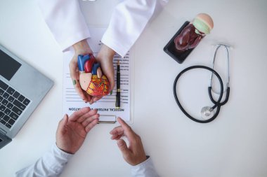 Doktorun elindeki gerçekçi kalp modeli, kalp rahatsızlığı olan hastaların sağlıklarına bakılması ve kalp hastalığı riski altındaki insanların düzenli kontrollere katılmaları için teşvik edilmesine yönelik kampanyanın sembolüdür..