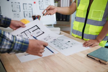 Mühendis ve mimarlardan oluşan bir ekip ev tasarımı ve inşaat bütçesine uygun inşaat fiyatlarını tartışıyor. Mühendis ve mimarlardan oluşan bir ekiple planlar ve belgeler kontrol ediliyor