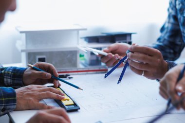 Mühendis ve mimarlardan oluşan bir ekip ev tasarımı ve inşaat bütçesine uygun inşaat fiyatlarını tartışıyor. Mühendis ve mimarlardan oluşan bir ekiple planlar ve belgeler kontrol ediliyor