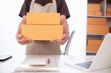paket kutuları paketleniyor ve çevrimiçi mağazanın sistemine çevrimiçi siparişler koyan müşterilere gönderilmeye hazır. Küçük bir KOBİ işadamı paketleri hazırladı ve teslimata hazır.