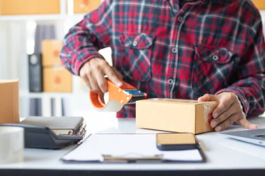 paket kutuları paketleniyor ve çevrimiçi mağazanın sistemine çevrimiçi siparişler koyan müşterilere gönderilmeye hazır. Küçük bir KOBİ işadamı paketleri hazırladı ve teslimata hazır.