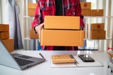 paket kutuları paketleniyor ve çevrimiçi mağazanın sistemine çevrimiçi siparişler koyan müşterilere gönderilmeye hazır. Küçük bir KOBİ işadamı paketleri hazırladı ve teslimata hazır.