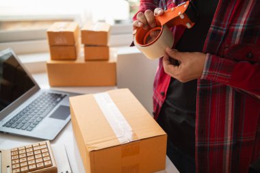 paket kutuları paketleniyor ve çevrimiçi mağazanın sistemine çevrimiçi siparişler koyan müşterilere gönderilmeye hazır. Küçük bir KOBİ işadamı paketleri hazırladı ve teslimata hazır.