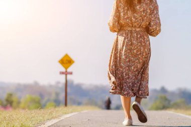 Bulanık bir görüntü, çiçekli bir elbise giyen bir kadın sabahın köründe yalnız başına sokakta yürüyor. Genç bir kadın, açık gökyüzünün arka planında yalnızlıkla koridorda tek başına yürüyor.