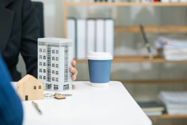 Emlakçı, emlak bürosundaki şirket projesinde emlak alım ve satımının terfisini sunmak için müşteriyle konuşuyor. Satın almaya karar vermek için mevcut promosyon.