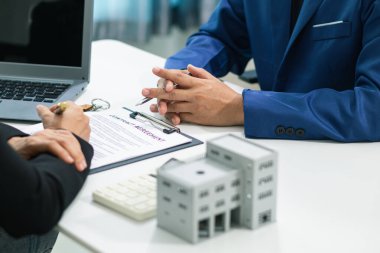 Emlakçı, emlak bürosundaki şirket projesinde emlak alım ve satımının terfisini sunmak için müşteriyle konuşuyor. Satın almaya karar vermek için mevcut promosyon.