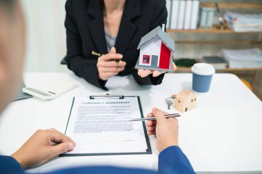 Emlakçı, emlak bürosundaki şirket projesinde emlak alım ve satımının terfisini sunmak için müşteriyle konuşuyor. Satın almaya karar vermek için mevcut promosyon.