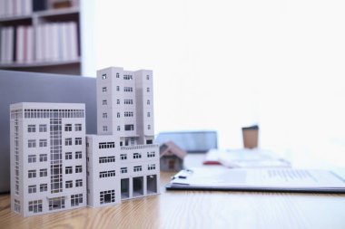 Emlak bürosundaki emlak acentesinin masasına yerleştirilen bina ve belgeleri, gayrimenkul almaya karar vermeden önce mülkü görmeye gelecek müşterilere hazırlanmak için düzenleyin..