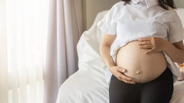 stock image The expectant mother put her hands on her belly lovingly because she felt the force of the baby in the womb, and she prayed to God with her faith and power to deliver the baby and she is safe