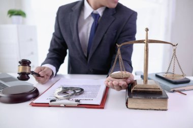 Bir avukatlık bürosundaki bir masaya, yargı sürecinde bir madalya ve adaletin sembolü olarak pirinç bir terazi yerleştirilir. Pirinç pulları mahkemedeki adaleti simgeliyor. Metin için boşluğu kopyala