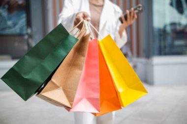 Bir alışveriş merkezinde alışveriş poşetleri tutan iş kadını, festival sırasında ihtiyaçlarını karşıladığı için mutlu. İçinde bir sürü ürün bulunan kağıt torbalar Asyalı iş kadınının elinde..