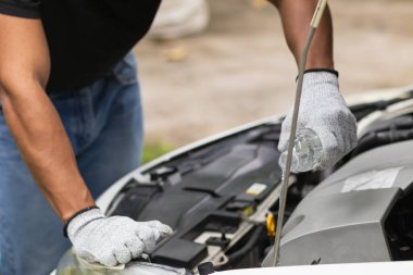 mechanic is checking car and adding water to radiator to increase the engine cooling capacity.  mechanic from the service center who was called by service center application is helping customer clipart