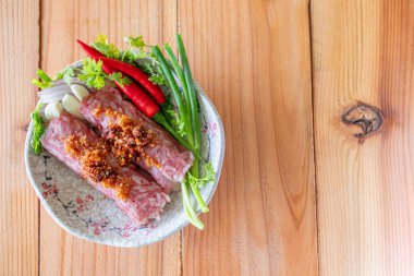 Kıyılmış domuz pirinci sarımsağı ve baharatlar karıştırılır ve yemeği terbiye etmek için bir çubuk haline getirilir. Ekşi bir tat verir çünkü bu, naem veya ekşi et denen bir Asya yemeği koruma türüdür..