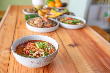 Khao Soi Chiang Tung bir kase içinde pilav eriştesi ve Chiang Tung usulü lezzetli bir çorba ile servis edilir. Lezzetli Khao Soi Chiang Tung, Tai Yai halkı arasında popüler bir erişte yemeği..