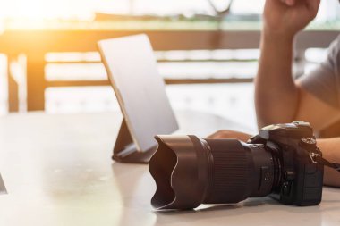 Fotoğrafçı kameradan görüntüleri bilgisayara aktarmaya ve müşterinin görüntülerini düzenlemeye hazırlanırken bir DSLR kamerası masanın üzerine yerleştirilir..