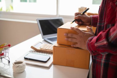 İşadamı, siparişleri olan ve malları göndermeden önce doğruluğunu kontrol eden müşterilerin talebini karşılamak için hisseleri kontrol ediyor. Siparişleri yerine getirmek için ürün siparişlerini ve stokları kontrol ediyorum..