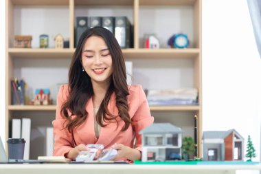 Asyalı iş kadını bir emlak komisyoncusu işletiyor ve büyük projeler için potansiyel alıcılara emlak mülklerini teklif ediyor ve emlak endüstrisi nüfusla birlikte büyümeye devam ediyor..