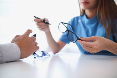 Göz doktorları hastanın göz anormalliklerini daha net görebilmeleri için inceliyor. Göz doktoru uygun gözlükleri önermek için görüşü inceliyor..