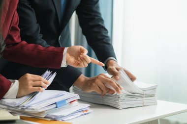 İki iş kadını, daha önce imzalanan belgelerin orijinalliğini doğrulamak için masadaki bir yığın belgeyi incelemek üzere birlikte çalışıyorlar..