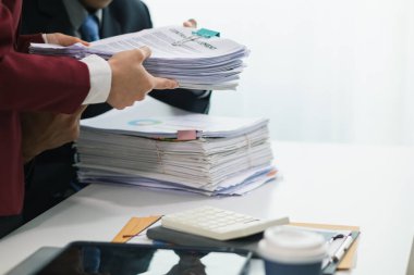 İki iş kadını, daha önce imzalanan belgelerin orijinalliğini doğrulamak için masadaki bir yığın belgeyi incelemek üzere birlikte çalışıyorlar..