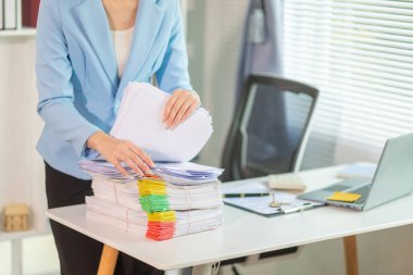 Masadaki belge yığınından önemli kontrat belgeleri arayan işadamı bir yatırımcıyla anlaşma imzaladığını doğruladı. İş adamı kontratta imzaladığı belgelerin doğruluğunu kontrol ediyor.