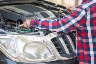 Adam uzun mesafeler kat etmeden önce düzgün ve güvenli bir şekilde tamir etmek için aracın motorunu ve durumunu kontrol ediyor. Adam güvenli bir yere gitmeden önce arabanın ve motorun durumunu kontrol ediyor..