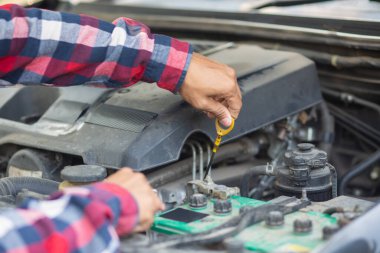 Adam uzun mesafeler kat etmeden önce düzgün ve güvenli bir şekilde tamir etmek için aracın motorunu ve durumunu kontrol ediyor. Adam güvenli bir yere gitmeden önce arabanın ve motorun durumunu kontrol ediyor..