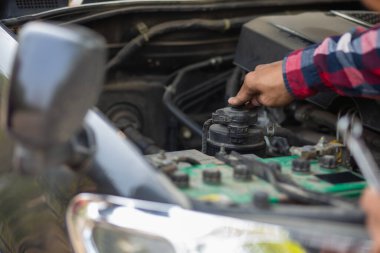 Adam uzun mesafeler kat etmeden önce düzgün ve güvenli bir şekilde tamir etmek için aracın motorunu ve durumunu kontrol ediyor. Adam güvenli bir yere gitmeden önce arabanın ve motorun durumunu kontrol ediyor..