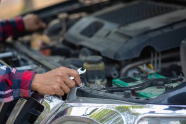 Adam uzun mesafeler kat etmeden önce düzgün ve güvenli bir şekilde tamir etmek için aracın motorunu ve durumunu kontrol ediyor. Adam güvenli bir yere gitmeden önce arabanın ve motorun durumunu kontrol ediyor..