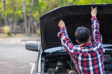 Adam uzun mesafeler kat etmeden önce düzgün ve güvenli bir şekilde tamir etmek için aracın motorunu ve durumunu kontrol ediyor. Adam güvenli bir yere gitmeden önce arabanın ve motorun durumunu kontrol ediyor..